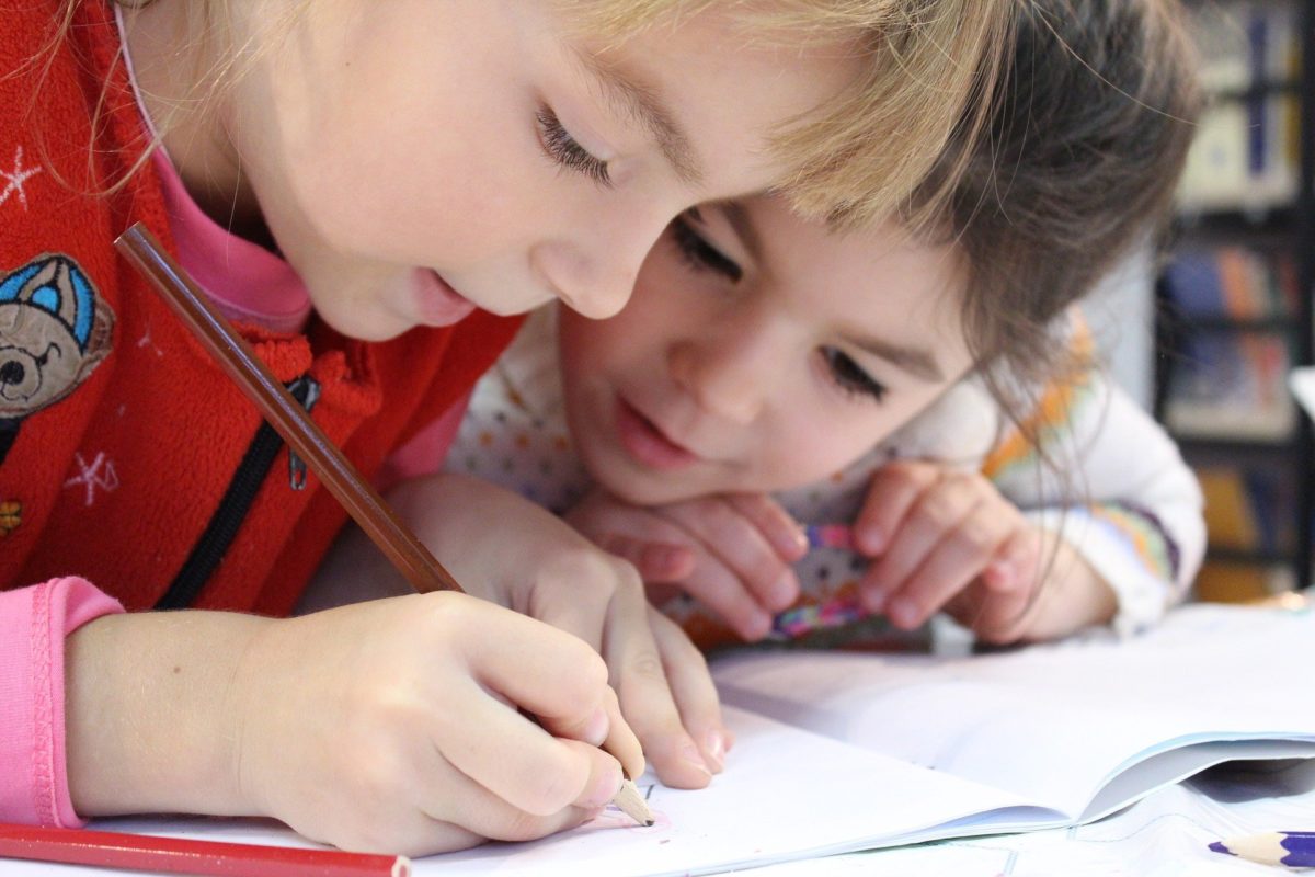 Two kids engrossed in a colouring book