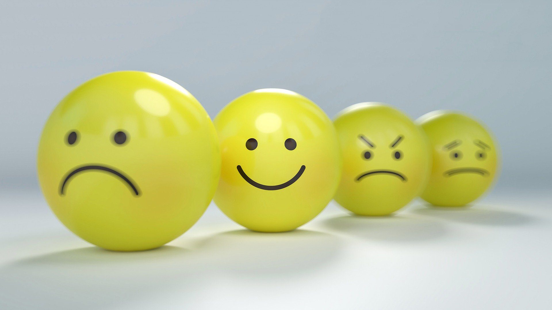 Photo of four yellow emojis pulling various faces – the focus is on the smiling one