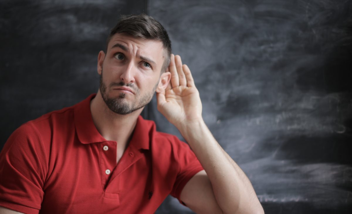 Man with his hand cupped behind hie ear, listening