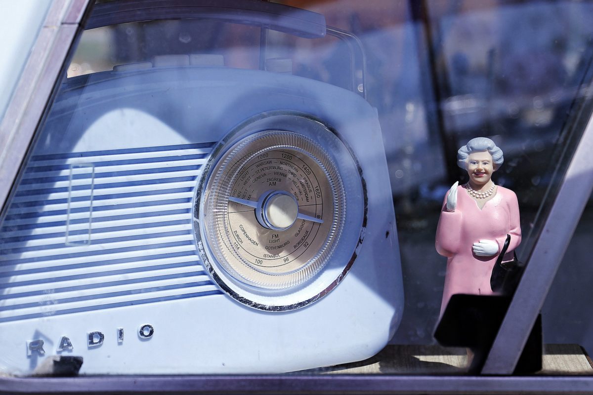 An old vintage radio and a figurine of the Queen