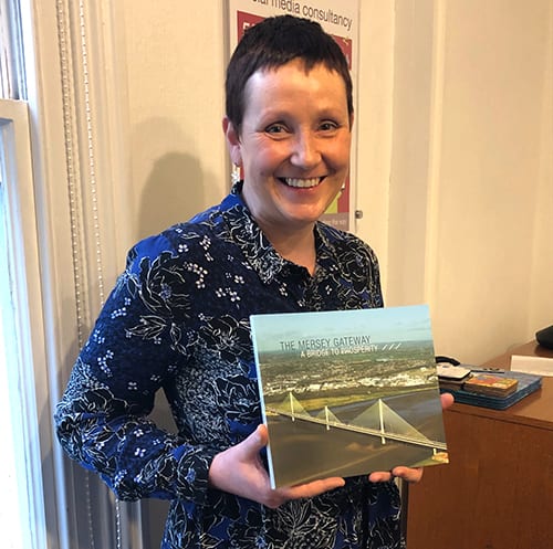 Photo of Paula holding a copy of the Mersey Gateway commemorative book