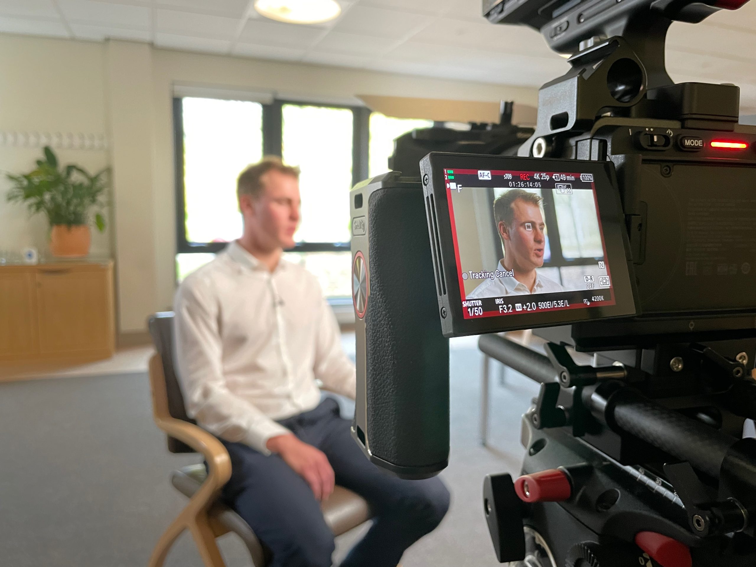 Photo of an interview being filmed showing the interviewee in the frame on the camera display