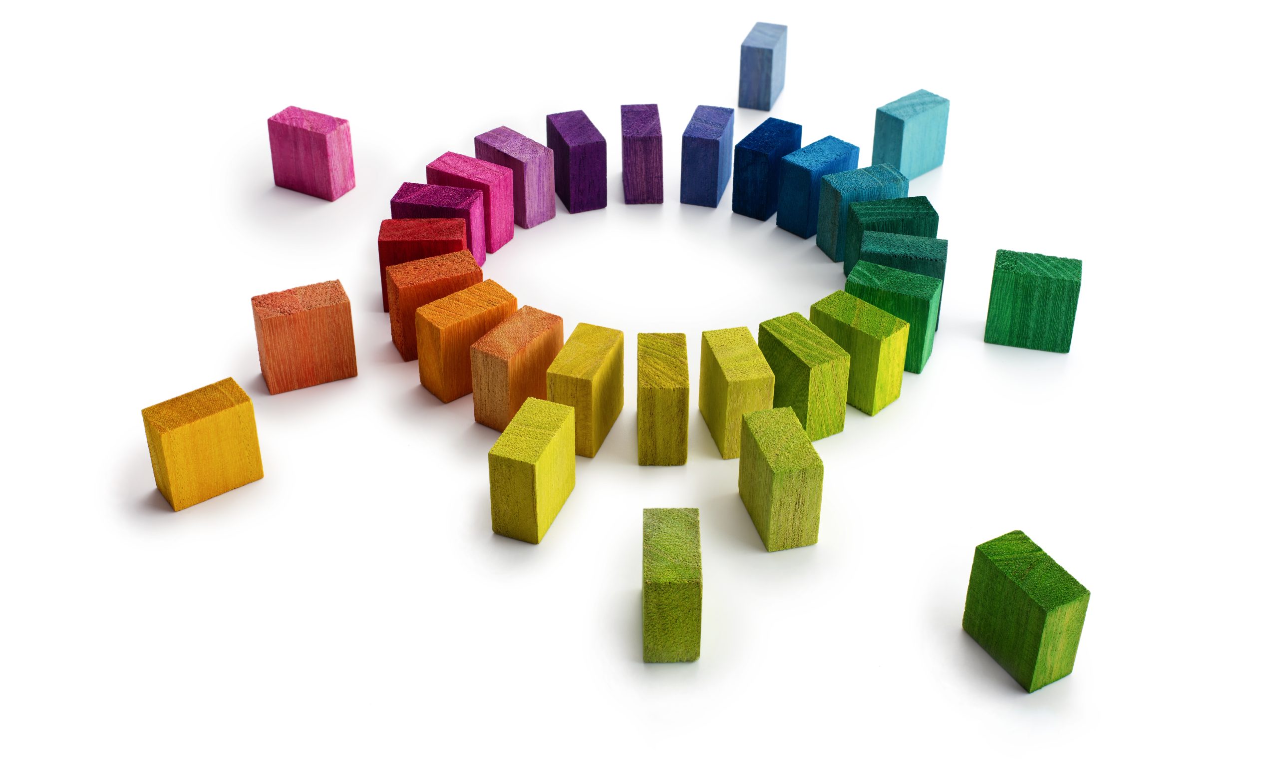 Image of rainbow of coloured blocks arranged in a circle with a number of additional coloured blocks randomly arranged around the edge of the circle.